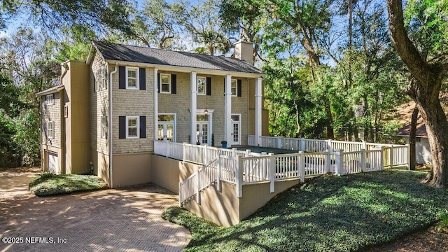 rear view of property featuring a chimney and an attached garage