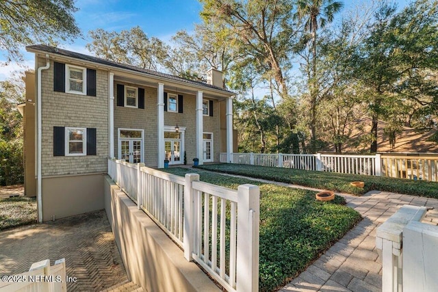 view of front of house featuring french doors, a front yard, fence, and a chimney