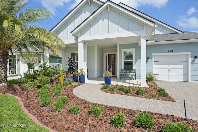 view of front of property featuring board and batten siding, a porch, an attached garage, and driveway