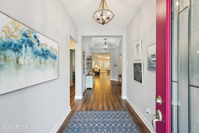 hallway with baseboards, an inviting chandelier, and dark wood finished floors
