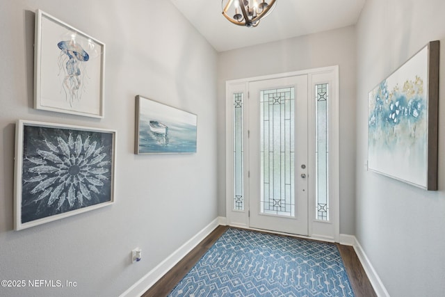 entryway featuring dark wood-style flooring, baseboards, and a chandelier