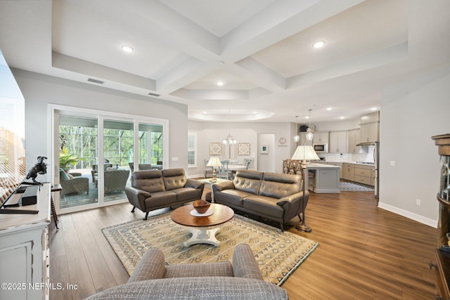 living room featuring beamed ceiling, wood finished floors, coffered ceiling, a notable chandelier, and baseboards