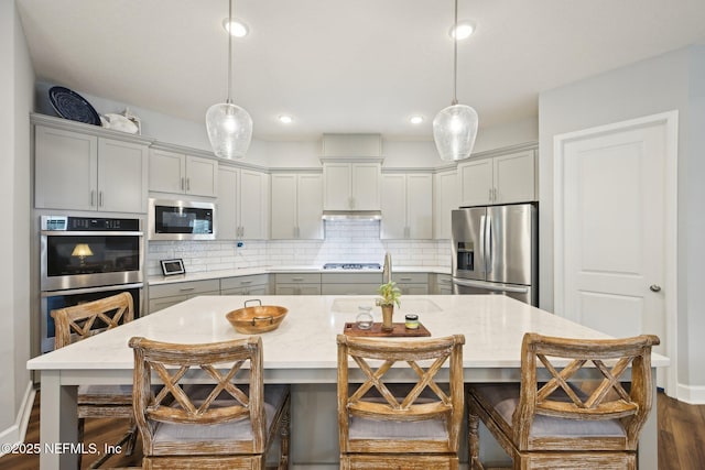 kitchen featuring a sink, backsplash, gray cabinetry, and stainless steel appliances