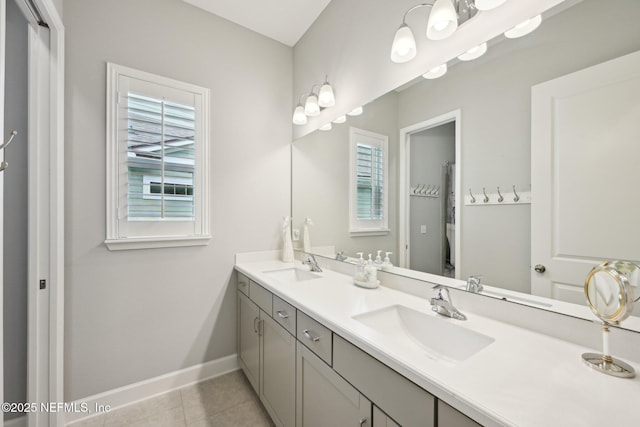 full bath with tile patterned floors, double vanity, a sink, and baseboards
