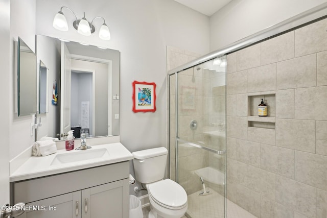 bathroom with a shower stall, vanity, and toilet