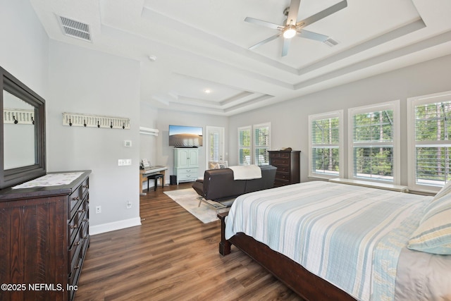 bedroom featuring a raised ceiling, dark wood-style flooring, multiple windows, and visible vents