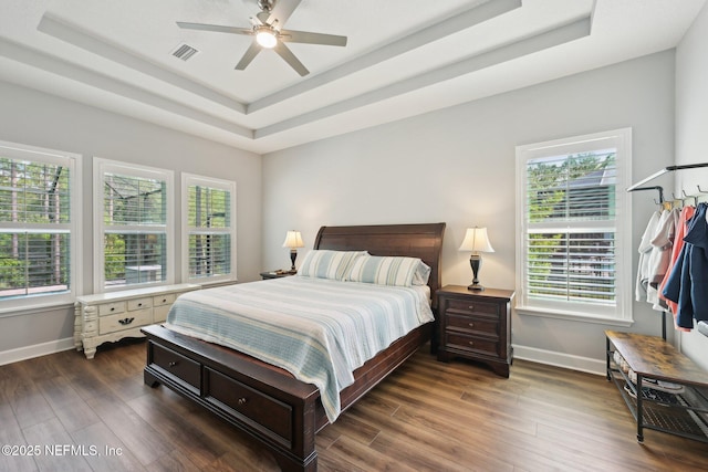 bedroom featuring visible vents, baseboards, a raised ceiling, and dark wood finished floors