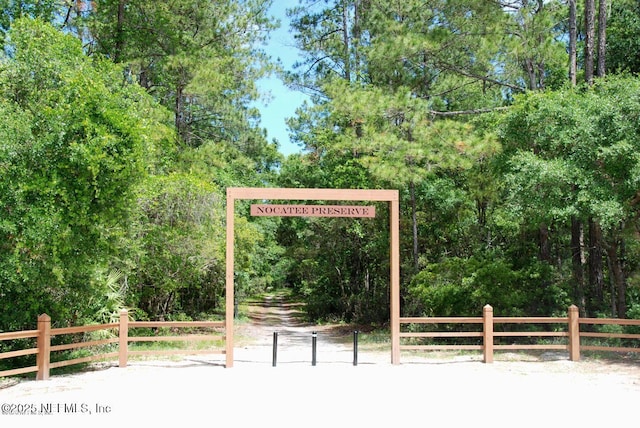 exterior space featuring a wooded view and fence