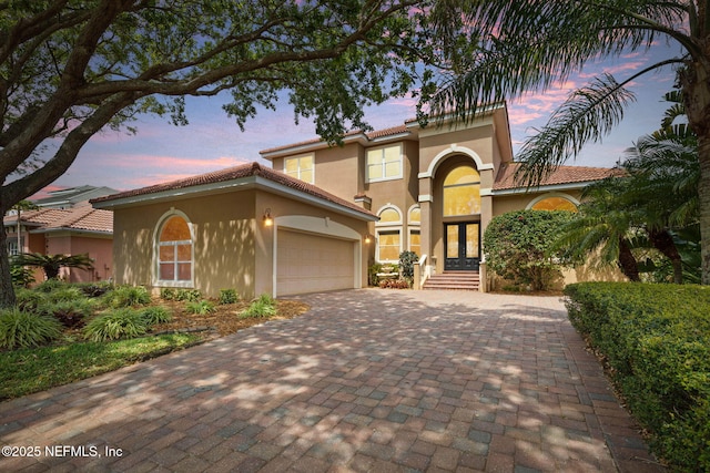 9 Cypresswood Dr, Palm Coast, FL 32137 - mediterranean / spanish-style home featuring a tiled roof, decorative driveway, an attached garage, stucco siding, and french doors
