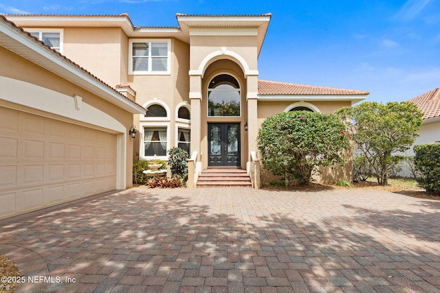 9 Cypresswood Dr, Palm Coast, FL 32137 - mediterranean / spanish-style house with a tile roof, stucco siding, french doors, decorative driveway, and a garage