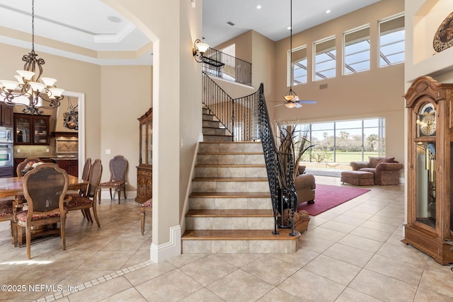 9 Cypresswood Dr, Palm Coast, FL 32137 - staircase featuring baseboards, arched walkways, ceiling fan with notable chandelier, a high ceiling, and tile patterned flooring