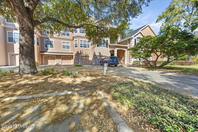 townhome / multi-family property with driveway, a garage, and stucco siding