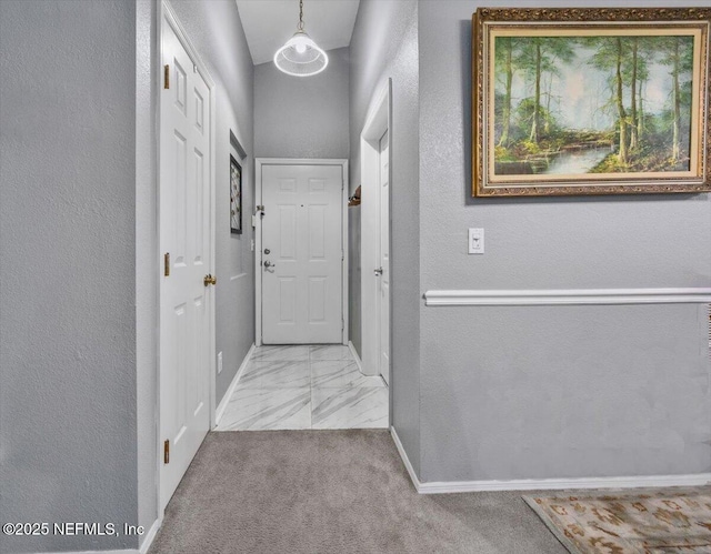 corridor with marble finish floor, baseboards, carpet floors, and a textured wall