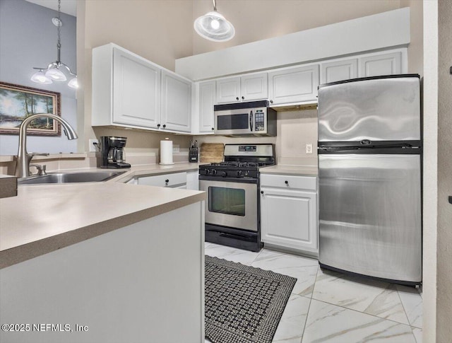 kitchen with marble finish floor, a towering ceiling, appliances with stainless steel finishes, a sink, and hanging light fixtures