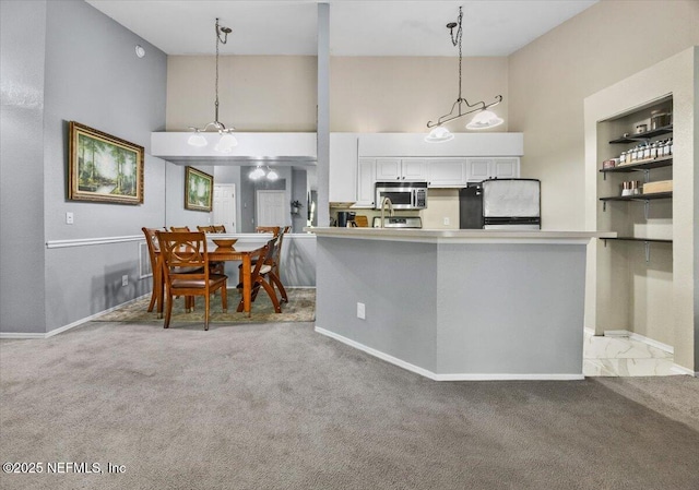 kitchen with fridge, white cabinetry, carpet, and stainless steel microwave