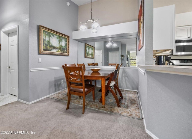 carpeted dining space featuring a towering ceiling, baseboards, and a chandelier