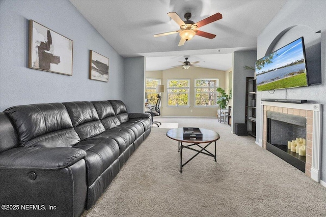 carpeted living room with lofted ceiling, ceiling fan, and a tile fireplace