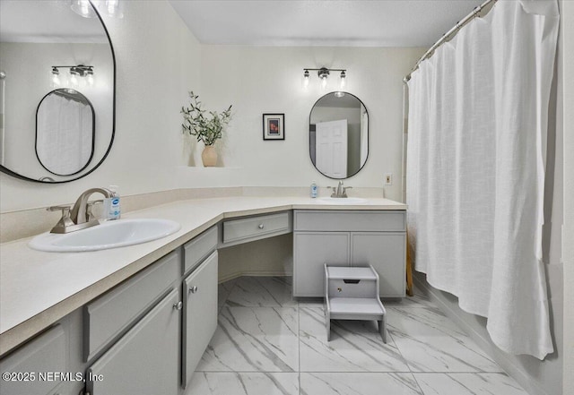 full bath featuring marble finish floor, double vanity, and a sink