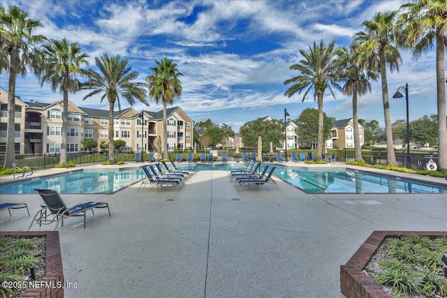 community pool with fence and a patio area