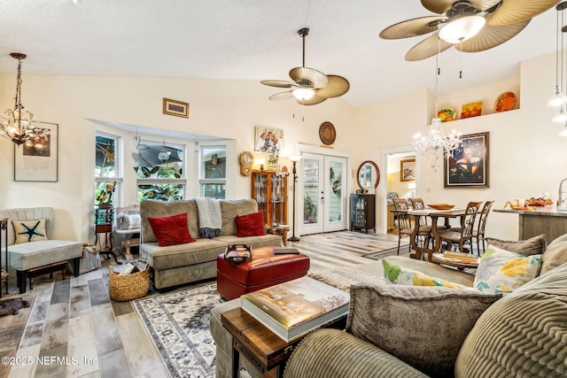living room featuring french doors, light wood-style flooring, ceiling fan with notable chandelier, and lofted ceiling