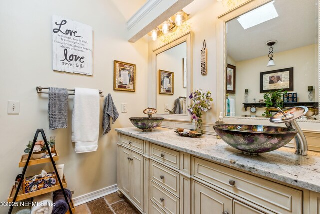 bathroom with vanity, baseboards, and a skylight