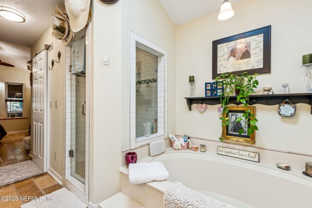 bathroom featuring a bath, a textured ceiling, and a stall shower