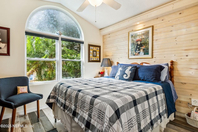 bedroom with baseboards, wood finished floors, vaulted ceiling, and wood walls