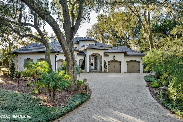 113 Cutter Ct, Ponte Vedra Beach, FL 32082 - mediterranean / spanish-style home featuring an attached garage, a chimney, decorative driveway, and stucco siding