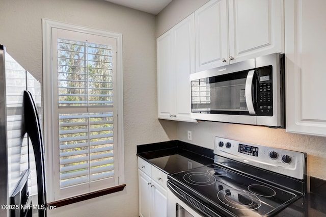 8539 Gate Pkwy W Unit 1121, Jacksonville, FL 32216 - kitchen featuring plenty of natural light, white cabinetry, dark countertops, and appliances with stainless steel finishes