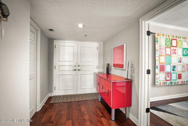 entrance foyer featuring a textured ceiling, visible vents, baseboards, and dark wood-style flooring