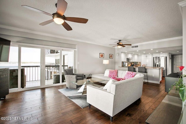 living room with ceiling fan, visible vents, crown molding, and dark wood finished floors
