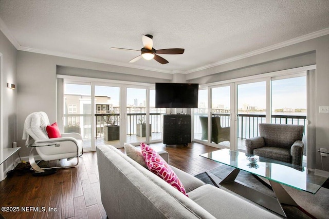 living room with dark wood-style flooring, a textured ceiling, baseboards, ornamental molding, and a ceiling fan