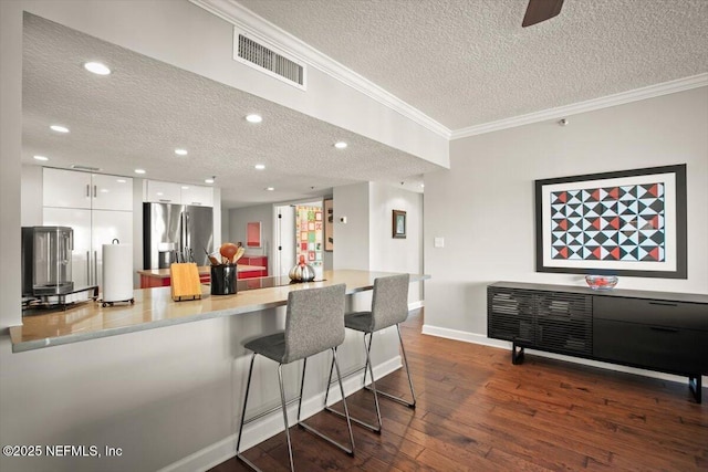 kitchen featuring modern cabinets, dark wood finished floors, stainless steel refrigerator with ice dispenser, visible vents, and white cabinets
