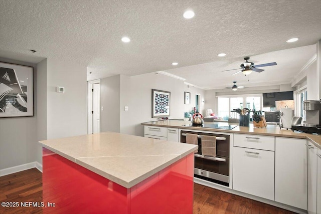 kitchen featuring white cabinetry, a ceiling fan, a kitchen island, and dark wood-type flooring