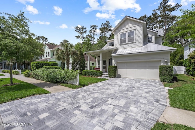 view of front of house featuring a standing seam roof, metal roof, decorative driveway, a front lawn, and an attached garage