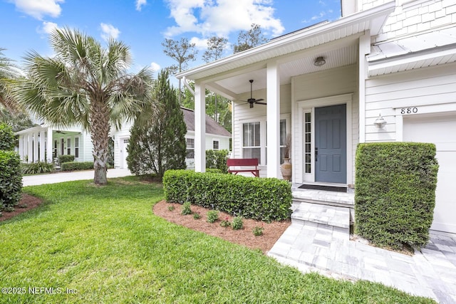 doorway to property featuring a lawn, a ceiling fan, and a porch