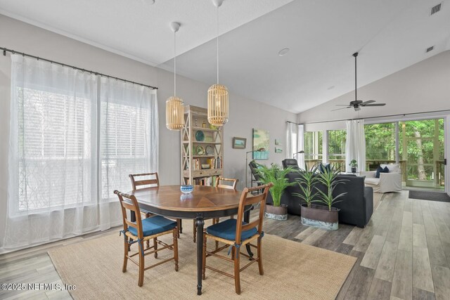 dining room featuring ceiling fan, vaulted ceiling, wood finished floors, and visible vents