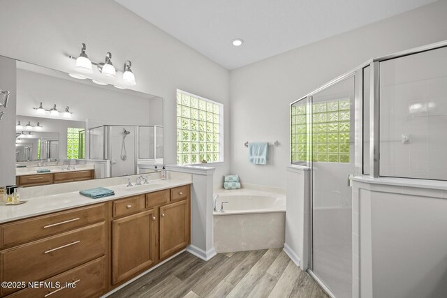 bathroom with a shower stall, wood finished floors, a garden tub, and vanity