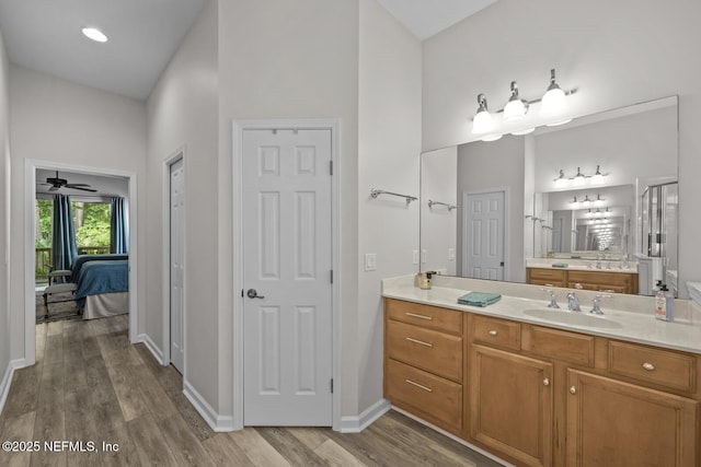 bathroom with vanity, wood finished floors, baseboards, ceiling fan, and connected bathroom