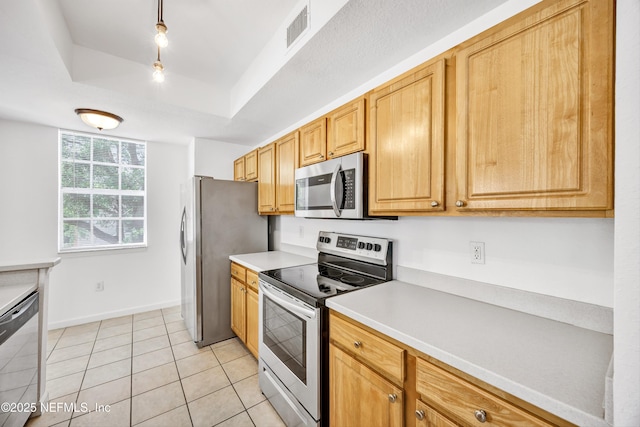kitchen featuring light countertops, a tray ceiling, light tile patterned floors, stainless steel appliances, and visible vents