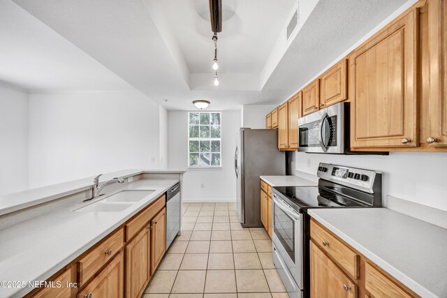 kitchen featuring light countertops, stainless steel appliances, a raised ceiling, a sink, and light tile patterned floors