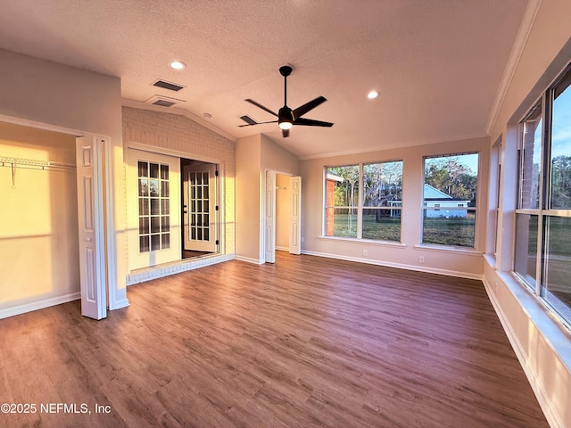 unfurnished living room with vaulted ceiling, a textured ceiling, ceiling fan, visible vents, and wood finished floors