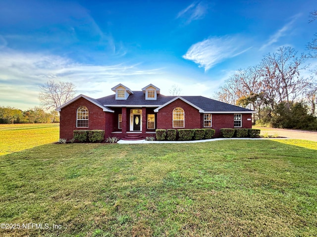 view of front of property with brick siding, a shingled roof, and a front lawn