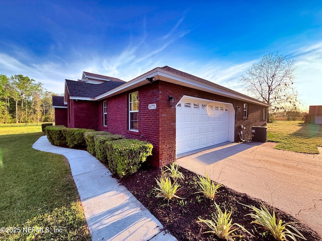 view of home's exterior featuring central AC unit, an attached garage, brick siding, driveway, and a yard