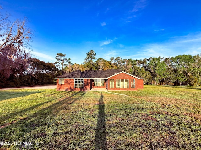 single story home with brick siding, a front yard, and driveway
