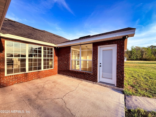 doorway to property with a patio, brick siding, and a yard