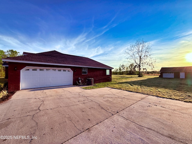 view of home's exterior with central air condition unit, a lawn, driveway, and brick siding