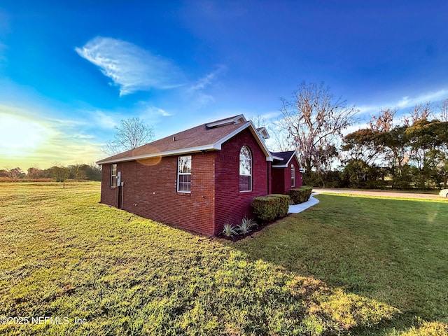 view of home's exterior featuring brick siding and a yard