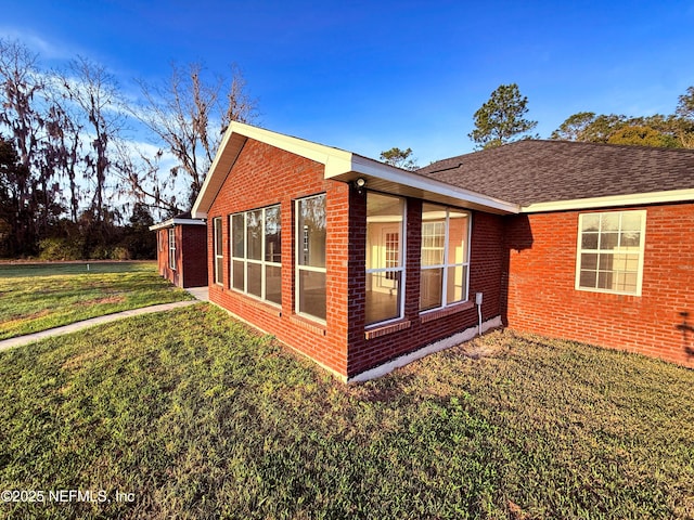 view of home's exterior with brick siding and a yard