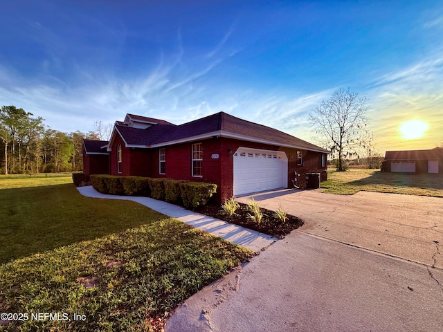 view of side of property featuring brick siding, concrete driveway, a yard, and an attached garage